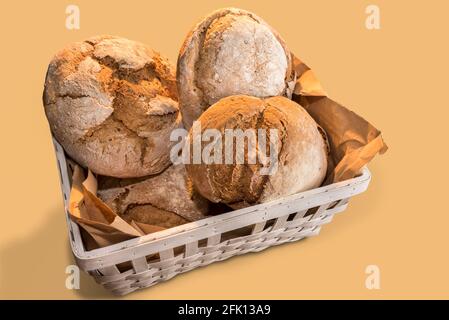 Freshly baked sourdough bread, large loaves in white wooden basket on beige background, top view Stock Photo