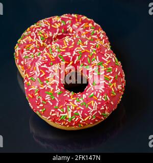 Two bright glazed donuts on dark minimal background close-up, top view Stock Photo