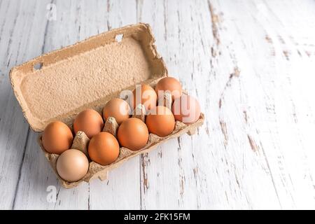 Chicken eggs in a corrugated container for packing eggs on a light wooden background. Eco-friendly packaging. Copy space Stock Photo