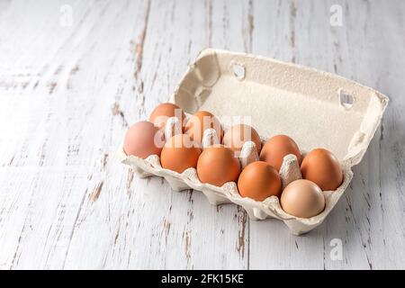 Chicken eggs in a corrugated container for packing eggs on a light wooden background. Eco-friendly packaging. Copy space Stock Photo