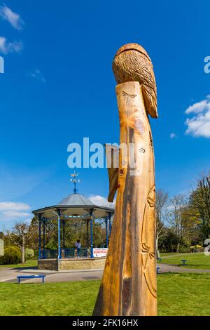 Pageant Gardens, Sherborne, Dorset UK on a warm sunny day in April - wooden carving and bandstand with Covid reminders Stock Photo