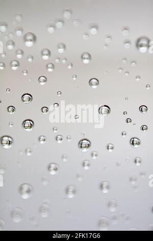 Drops of water from rainning on glass. Selective focus. white gray clouds background pattern texture. Stock Photo