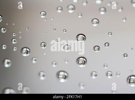 Drops of water from rainning on glass. Selective focus. white gray clouds background pattern texture. Stock Photo