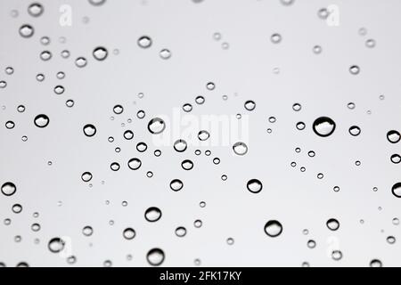 Drops of water from rainning on glass. Selective focus. white gray clouds background pattern texture. Stock Photo