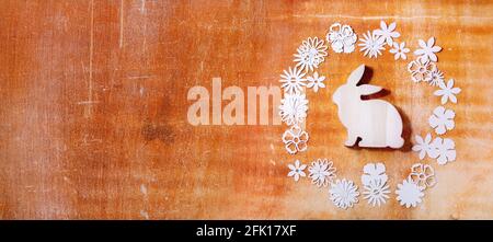 Easter banner with bunny rabbit with different paper flowers around over orange stone background. Flat lay, copy space. Easter holiday greeting card c Stock Photo