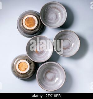 Set of empty craft ceramic bowls cover by grey texture glaze over gray background. Flat lay Stock Photo