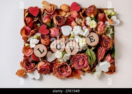Beautiful botanical composition for st. Valentines Day. Creative layout with dry roses, petals, white flowers, small hearts and LOVE letters in white Stock Photo