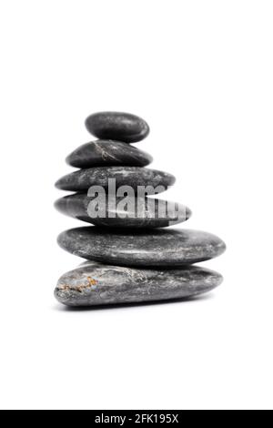 Zen stones or black pebbles stacked on top of each other like a pyramid, isolated on white background. Harmony, balance and meditation, spa, massage. Stock Photo