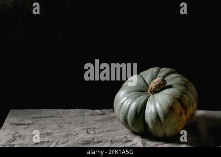 Blue pumpkin on linen tablecloth. Dark still life. Autumn harvest. Copy space Stock Photo