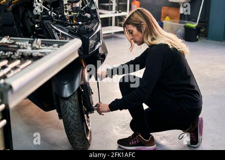 Mechanic woman works in a garage repairing a motorcycle Stock Photo