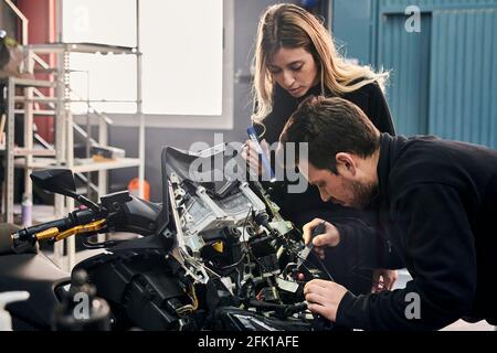 A woman and a man are working together in a mechanic shop Stock Photo