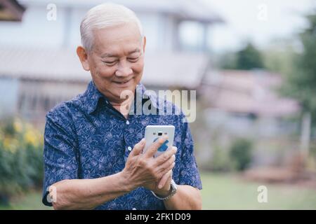 Happy asian elder man using smartphone. Stock Photo