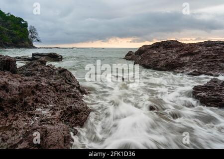 PANAMA, PANAMA - Apr 25, 2021: Wave breaking on a rocky Beach, sunset Stock Photo