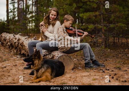 Family duet brother and sister, boy and girl, teenagers play trumpet a Stock Photo