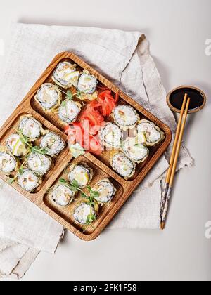Assorted hot rolls with eel, Japanese omelet, cream cheese, fried onions and unagi sauce with fresh herbs. Japanese food on a bamboo platter, bamboo s Stock Photo