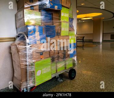 A shrink-wrapped handcart towering with packages from Amazon, Walmart and Hello Fresh among others sits unattended in an apartment building lobby the Chelsea neighborhood  of New York on Saturday, April 17, 2021. (© Richard B. Levine)