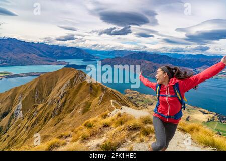 Travel post Covid-19 concept. Pent-up traveling demand concept. Hiker jumping of joy funny - woman hiking in New Zealand laughing having fun, joyful Stock Photo