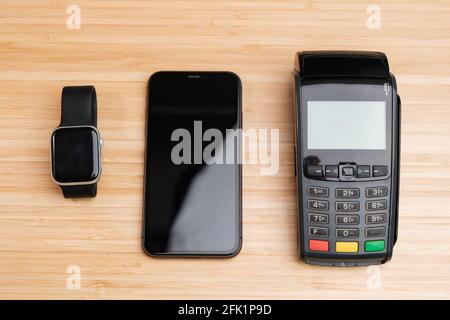 POS terminal, mobile phone, smartwatch for contactless payment on the wooden desk Stock Photo