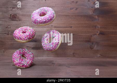 Creative food concept: levitating dounuts on wooden background Stock Photo