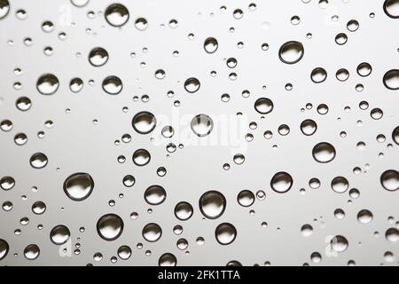 Drops of water from rainning on glass. Selective focus. white gray clouds background pattern texture. Stock Photo