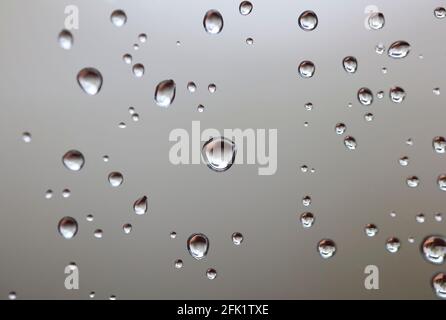 Drops of water from rainning on glass. Selective focus. white gray clouds background pattern texture. Stock Photo