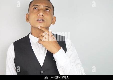 Handsome Indian man in formal wear deeply thinking looking up on a white background Stock Photo
