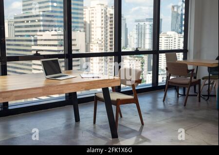 Interior of nobody modern office with laptop, clipboard on wooden desk and chair in busuness district Stock Photo