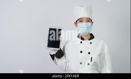 Chef wearing face protective medical mask or respirator for protection from virus disease. Food safety and coronavirus pandemic. chef posing gesture r Stock Photo