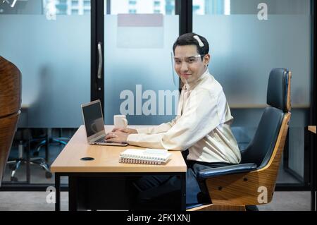 Happy young asian transvestite office worker working with laptop and document at desk in the office Stock Photo