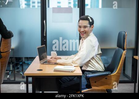 Happy young asian transvestite office worker working with laptop and document at desk in the office Stock Photo