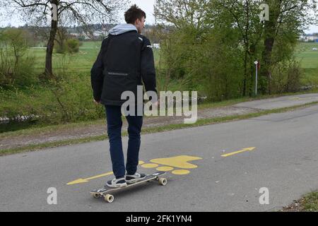 Teenager on skateboard on a roller blade  asphalt track with yellow icons of roller skate and arrows showing in opposite directions. Stock Photo