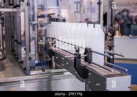 White bottles on conveyor belt of liquid filling machine Stock Photo