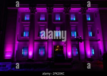 Four-story heritage building with roman columns illuminated at night with bright purple colour-changing lights for a winter festival Stock Photo