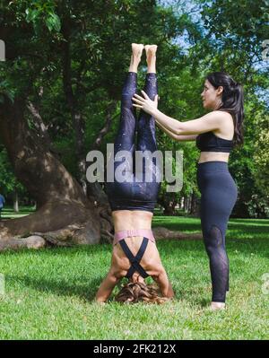 yoga instructor teaching a female student in a park. They practice yoga on the grass Stock Photo