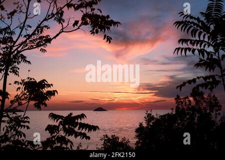 Selective focus .Heart shaped natural frame from branches and clouds.  Peaceful seascape . An island at far. Stock Photo