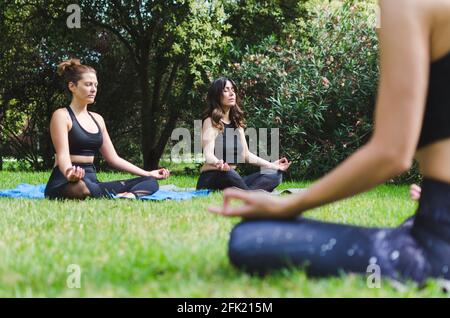 Three young women meditating in the park Stock Photo