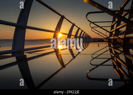 Sunset reflections on a metal seat on Aberavon promenade in Port Talbot, South Wales UK Stock Photo