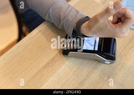 Unrecognizable man making wireless or contactless payment using smartwatch over nfc technology, apply to payment terminal. Concept e-commerce, people Stock Photo