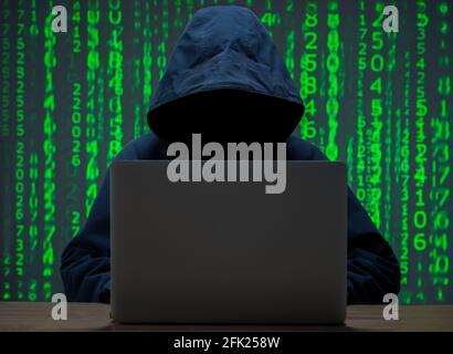 The hacker is in front of his computer. Digital figures in the background Stock Photo