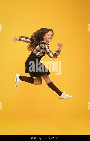 Break into. Feel inner energy. Girl with long hair jumping on yellow background. Carefree kid summer holiday. Time for fun. Active girl feel freedom Stock Photo