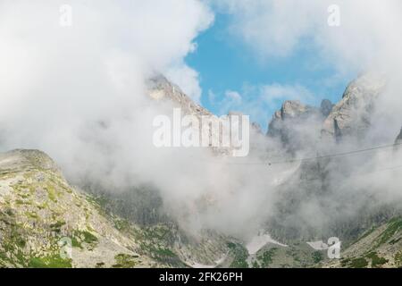 Panoramic view of rocky mountains covered with fluffy clouds.  Stock Photo