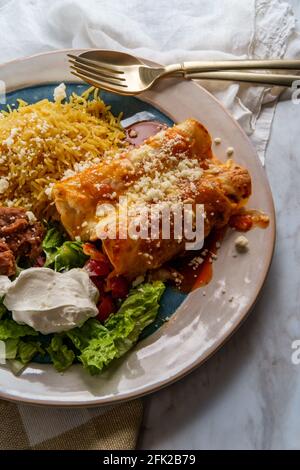 Traditional Mexican enchiladas dinner served with rice and refried pinto beans Stock Photo