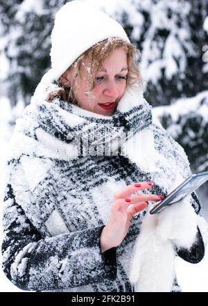 A young woman in winter uses a mobile phone. Stock Photo