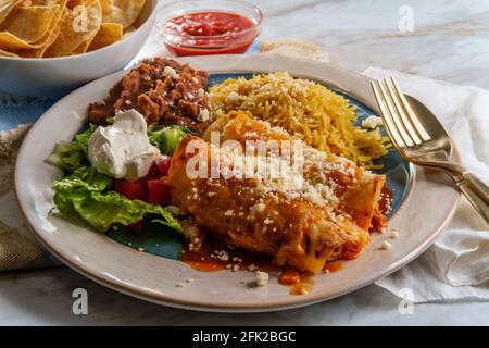 Traditional Mexican enchiladas dinner served with rice and refried pinto beans Stock Photo