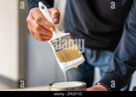 Close up on white paint brush in the hand of unknown man hobby painting and renovation repairing concept Stock Photo