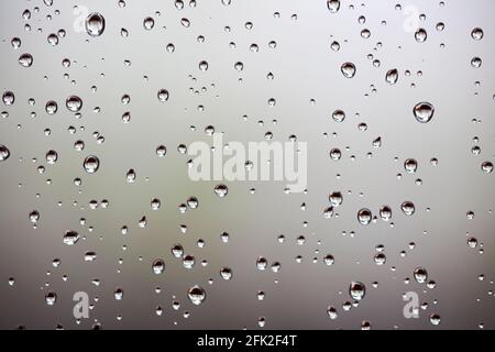 Drops of water from rainning on glass. Selective focus. white gray clouds background pattern texture. Stock Photo