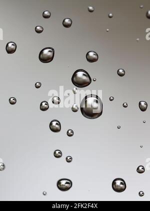 Drops of water from rainning on glass. Selective focus. white gray clouds background pattern texture. Stock Photo