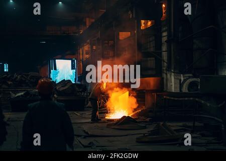 Worker in blast furnace factory interior. Metal casting process in metallurgical plant. Stock Photo