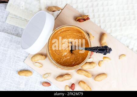 Top view of fresh homemade crunchy peanut butter with nuts on light wooden background in the kitchen. Stock Photo