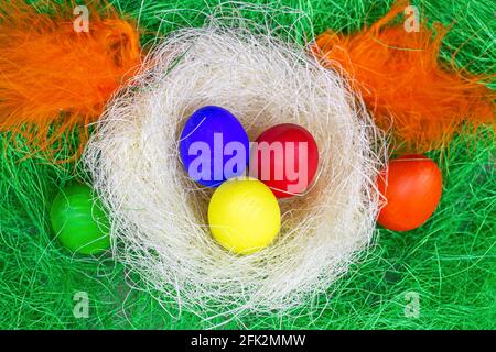 Top view colorful painted Easter eggs decorations in the nest on light green background. Stock Photo